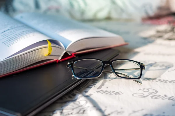 Laptop with book and glasses on bed — Stock Photo, Image