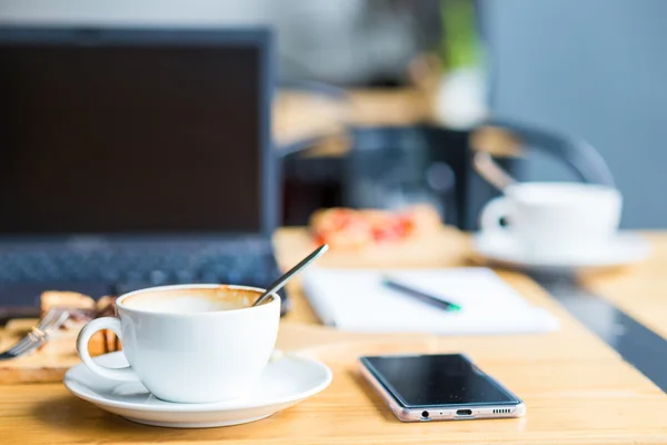 Laptop com xícara de café e telefone na mesa de madeira velha . — Fotografia de Stock
