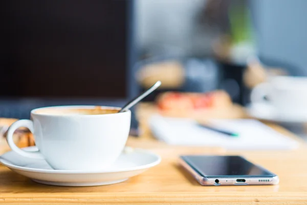 Laptop with cup of coffee and telephone on old wooden table. — Stock Photo, Image