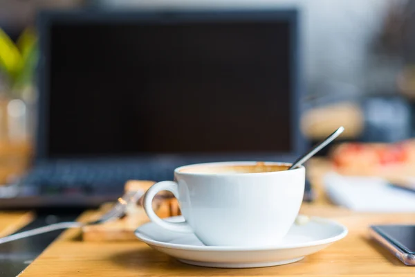 Laptop med kopp kaffe och telefon på gamla träbord. — Stockfoto