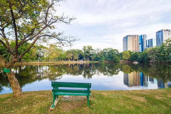 Banco del parque cerca del estanque en una ciudad tranquila en un día soleado — Foto de Stock