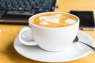 İşyeri dizüstü dizüstü bilgisayar ve lattte sanat kahve ile
