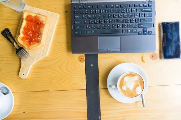 Flat lay material de escritório com telefone inteligente laptop café da manhã doce um — Fotografia de Stock