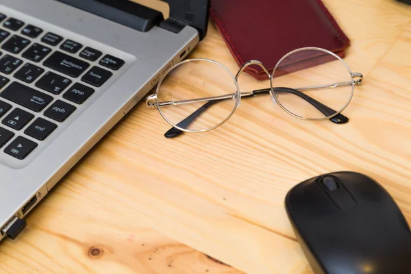 Computer portatile con smartphone e occhiali sul tavolo in legno hi — Foto Stock