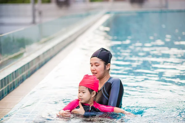 Ung aktiv mamma ha kul i en pool med asiatiska kid — Stockfoto