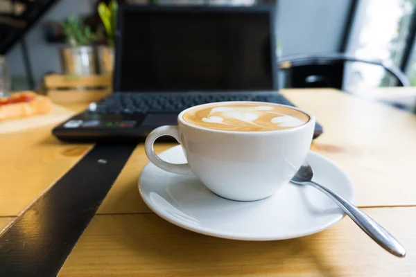 Latte art koffie cup en laptop voor het bedrijfsleven. — Stockfoto