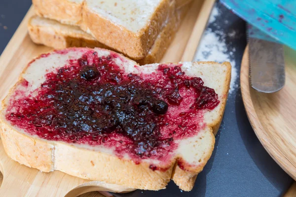 Bröd och svarta vinbär sylt på trä platta — Stockfoto