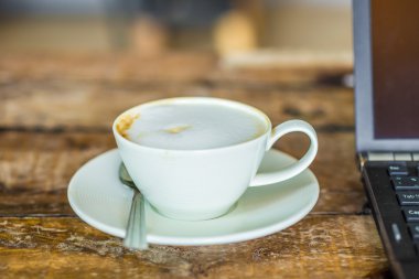 Dizüstü bilgisayar ve latte kahve sanat kafe, ahşap masa üzerinde çalışma alanı