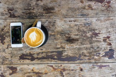Latte Kahve Kupası ve ahşap masa iş için cep telefonu