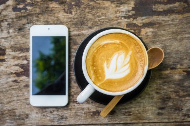 Latte Kahve Kupası ve ahşap masa iş için cep telefonu