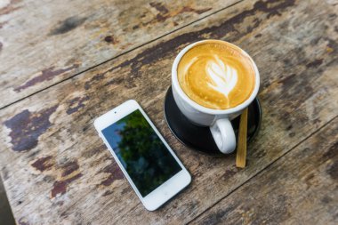 Latte Kahve Kupası ve ahşap masa iş için cep telefonu