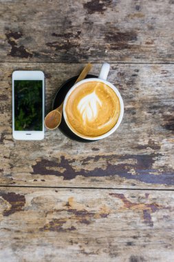 Latte Kahve Kupası ve ahşap masa iş için cep telefonu