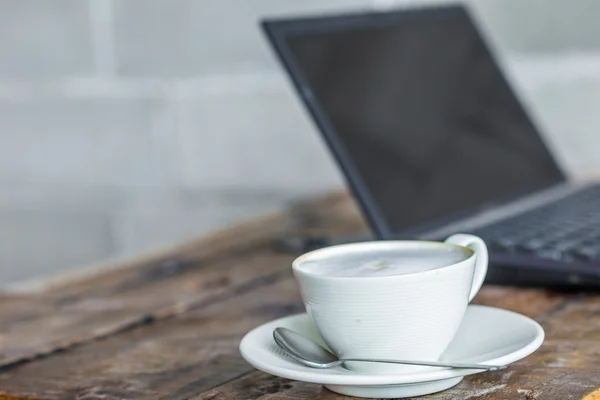 Spazio di lavoro su tavolo di legno di computer portatile e caffè di latte — Foto Stock