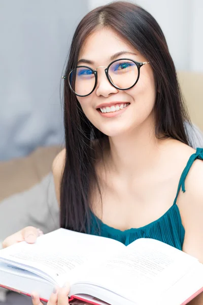 Asiatiska nörd kvinna läser en bok och leende — Stockfoto
