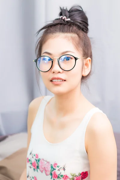 Счастливая азиатская молодая студентка носит очки дома — стоковое фото