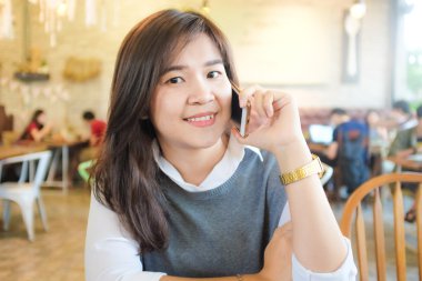 Güzel Asyalı genç kadın co otururken cep telefonu kullanarak