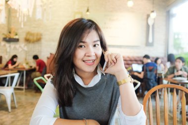 Güzel Asyalı genç kadın co otururken cep telefonu kullanarak