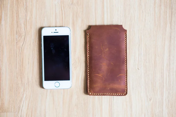 Genuine leather phone case on wood background