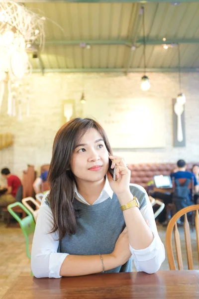 Ділові азіатські жінки використовують мобільний телефон, сидячи в кав'ярні мистецтва — стокове фото