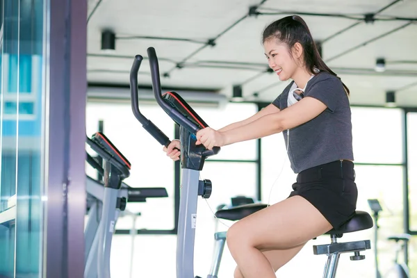 Hermosa mujer asiática en forma haciendo ejercicio en el gimnasio en bicicleta — Foto de Stock