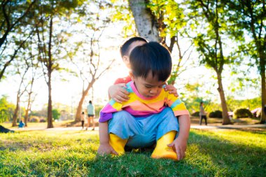 Bir grup mutlu çocuk bahar parkında yeşil çimlerde oynuyorlar gün batımı ışığı