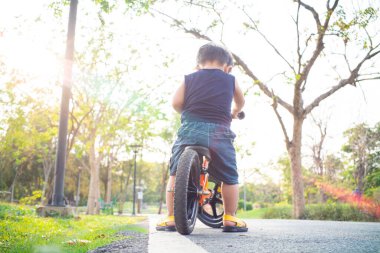 Şehir parkında dengeli bisikleti olan sevimli küçük çocuk sporcusu çocuk.