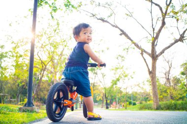 Şehir parkında dengeli bisikleti olan sevimli küçük çocuk sporcusu çocuk.