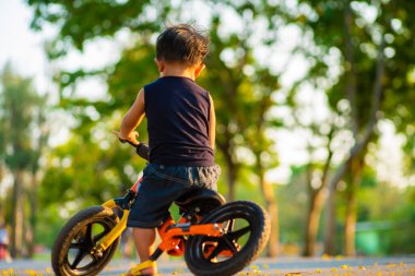 Şehir parkında dengeli bisikleti olan sevimli küçük çocuk sporcusu çocuk.