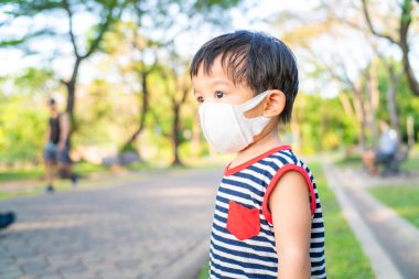Dışarıda koruyucu giyinmiş küçük Asyalı çocuk 2.5 ilaç maskesi, çocuk portresi..