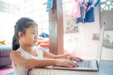 Evde dizüstü bilgisayarda kelime yazan mutlu Asyalı kız.