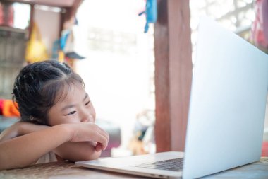 Evde dizüstü bilgisayarda kelime yazan mutlu Asyalı kız.