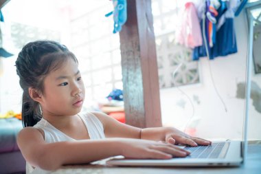 Evde dizüstü bilgisayarda kelime yazan mutlu Asyalı kız.