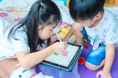 Çocuklar evde oynarken tablet bilgisayar kalemiyle resim çiziyorlar çocuklar sanat eğitimi alıyorlar