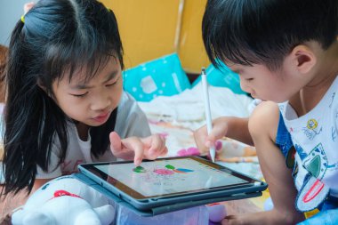 Mutlu çocuk ve kız evde uzanıyor ve bilgisayar tableti eğitim konseptiyle birlikte oynuyorlar.