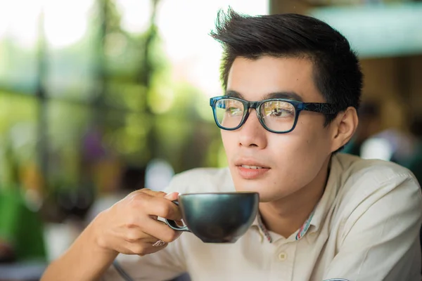 Asyalı Gözlüklü Adamı Sıcak Sütlü Kahve Içiyor Kafede Oturuyor — Stok fotoğraf