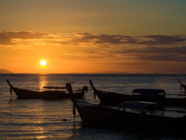 Sahilde gün batımında dramatik gökyüzü, doğayı bulutlandırıyor.