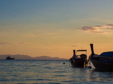Sahilde gün batımında dramatik gökyüzü, doğayı bulutlandırıyor.