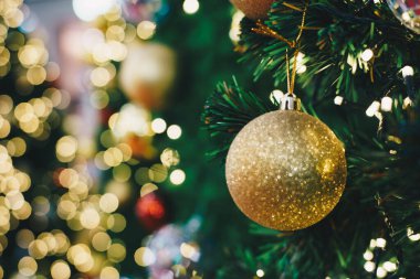 Çam ağacında asılı duran altın lüks Noel balosu bulanık bokeh simleri arka planda Xmas Festisal