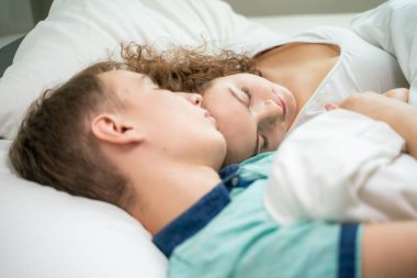 Beyaz yatakta uyuyan mutlu beyaz bir çift. Aşk romantizmi. Sevgililer Günü kavramı.