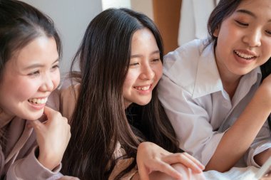 Bir grup güzel Asyalı kadın yataklarında uzanıp gülüyor ve sohbet ediyorlar. Moda mankenleri evde buluşmaktan zevk alıyorlar.