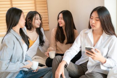 Sıradan giyinmiş bayan iş arkadaşı Asyalı kadınlar kahve içiyorlar ve fikir tartışıyorlar.