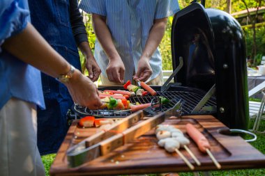 Park 'ta barbekü ızgara yemek partisi veren Asyalı mutlu bir arkadaş.