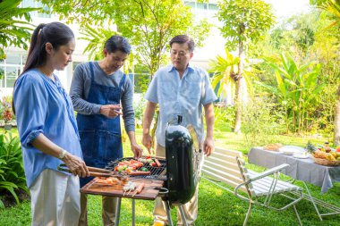 Park 'ta barbekü ızgara yemek partisi veren Asyalı mutlu bir arkadaş.