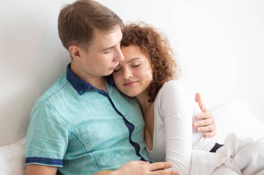 Romantik aşk çifti beyaz yataklı beyaz bir çiftte sevişiyor.