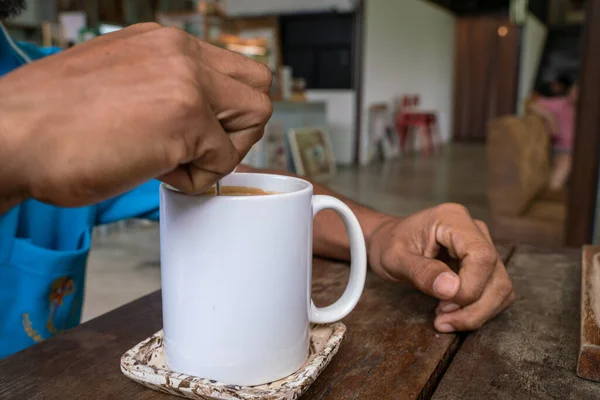 Man hand stir americano coffee cup on wood table in cafe shop