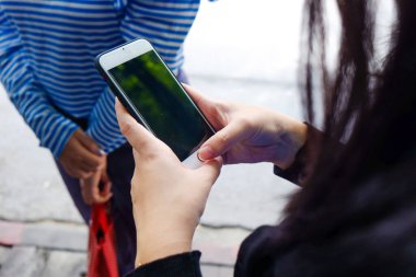 Gündüz atmosferik şehirde kadınlar ekranda akıllı telefonu işaret ediyor, hipster kadın elini kullanıyor ve cep telefonuna mesaj atıyor.