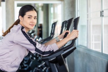 Zeki Asyalı güzel kadınlar spor salonunda bisikletle egzersiz yaparlar. Sağlıklı bir yaşam tarzı.