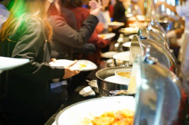 Bir grup insan açık büfeden kendi yemeklerini kapıyor.