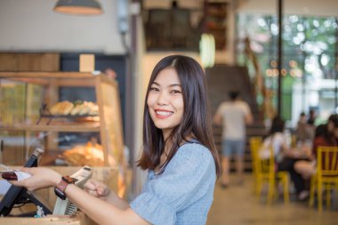 Kafedeki bir kafede genç Asyalı kadın kahve sipariş ediyor.