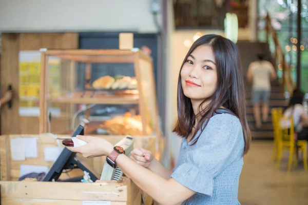 Young asian woman ordering coffee at the counter in a cafe business women in cafe